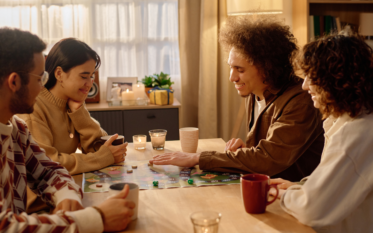 Friends laughing over a board game at a warm kitchen table