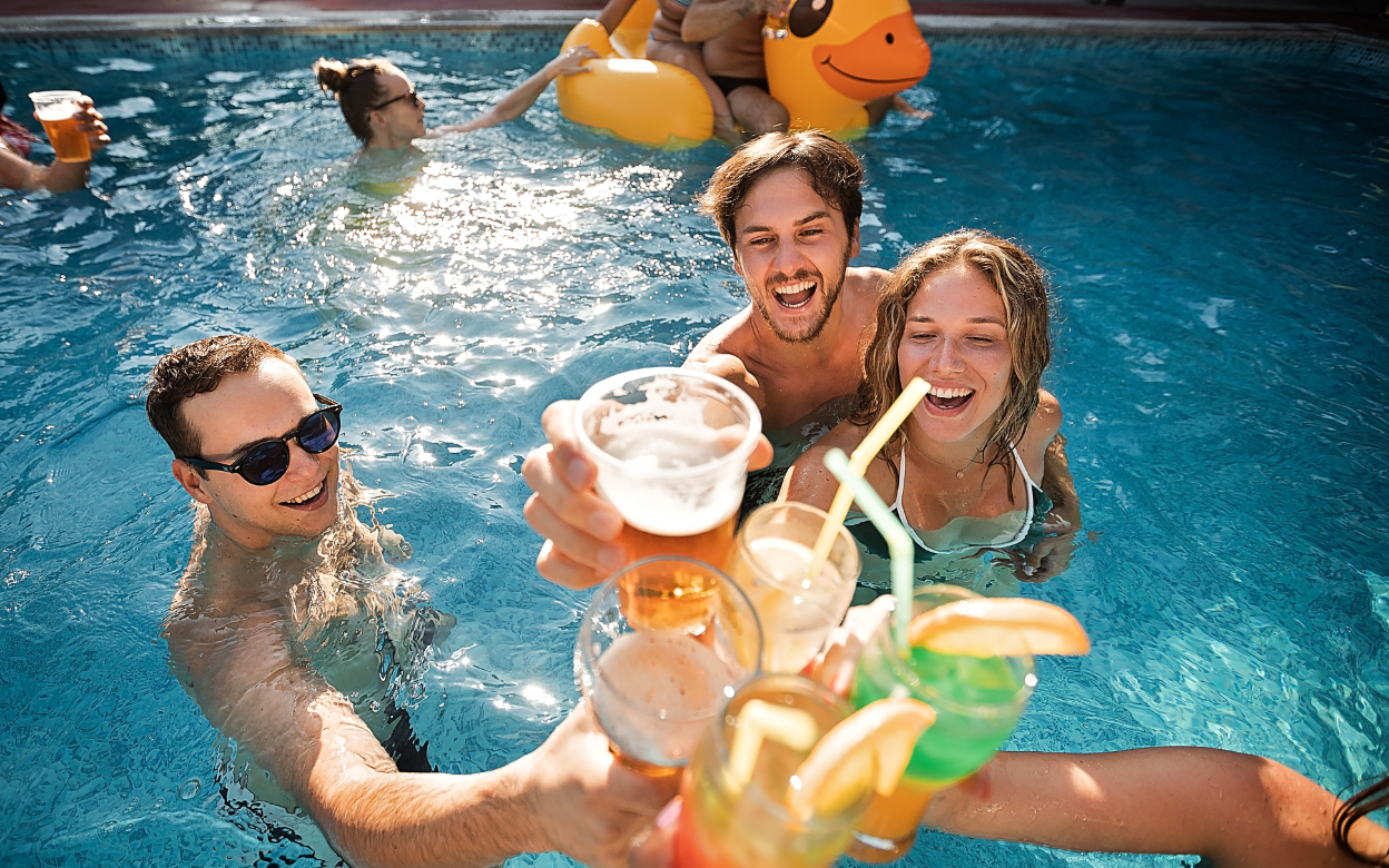 Friends celebrating with drinks in a pool